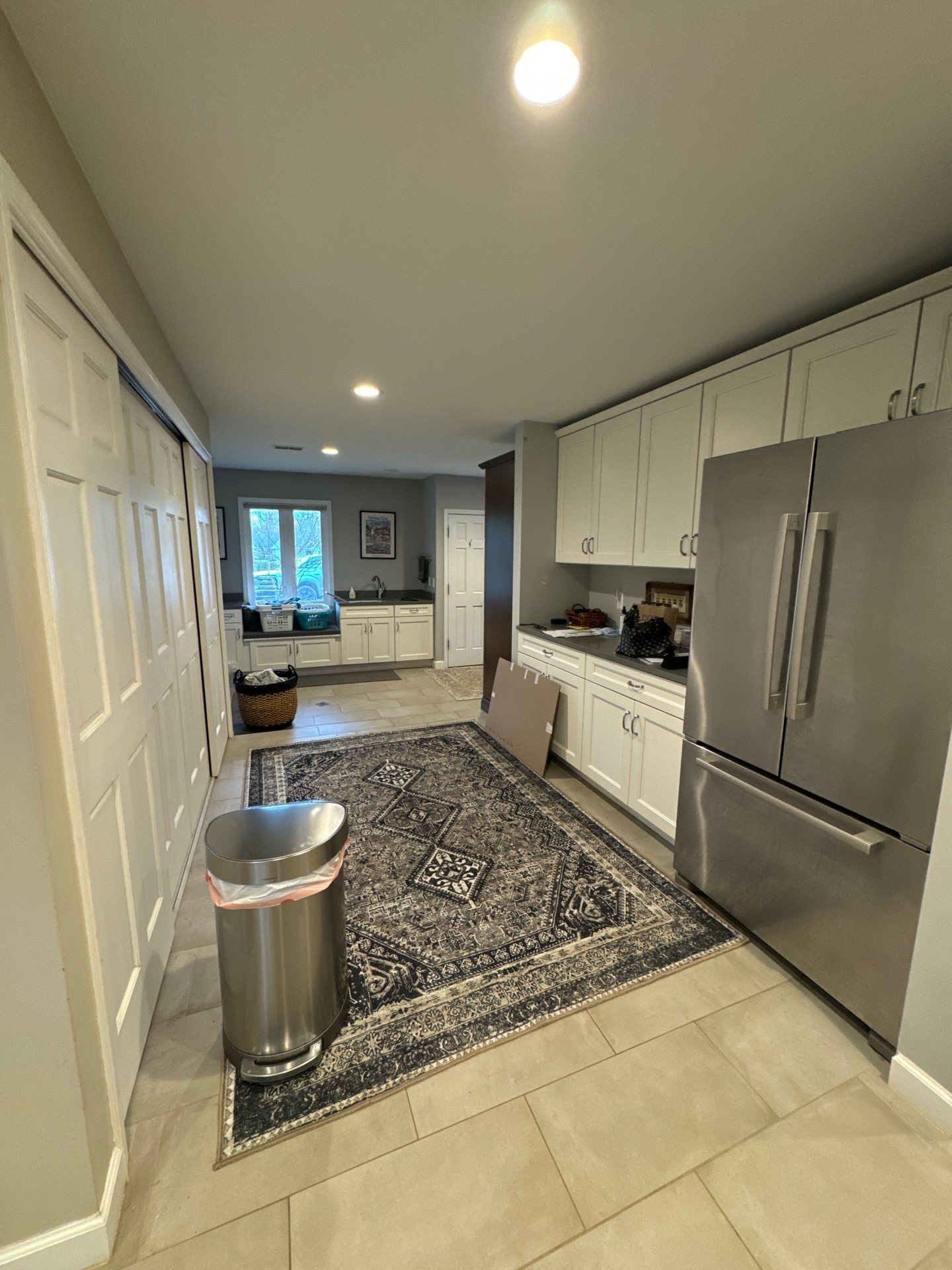 Professional interior painting for a modern kitchen and laundry room A bright, freshly painted kitchen and laundry room with light gray walls, white cabinets, and stainless steel appliances.