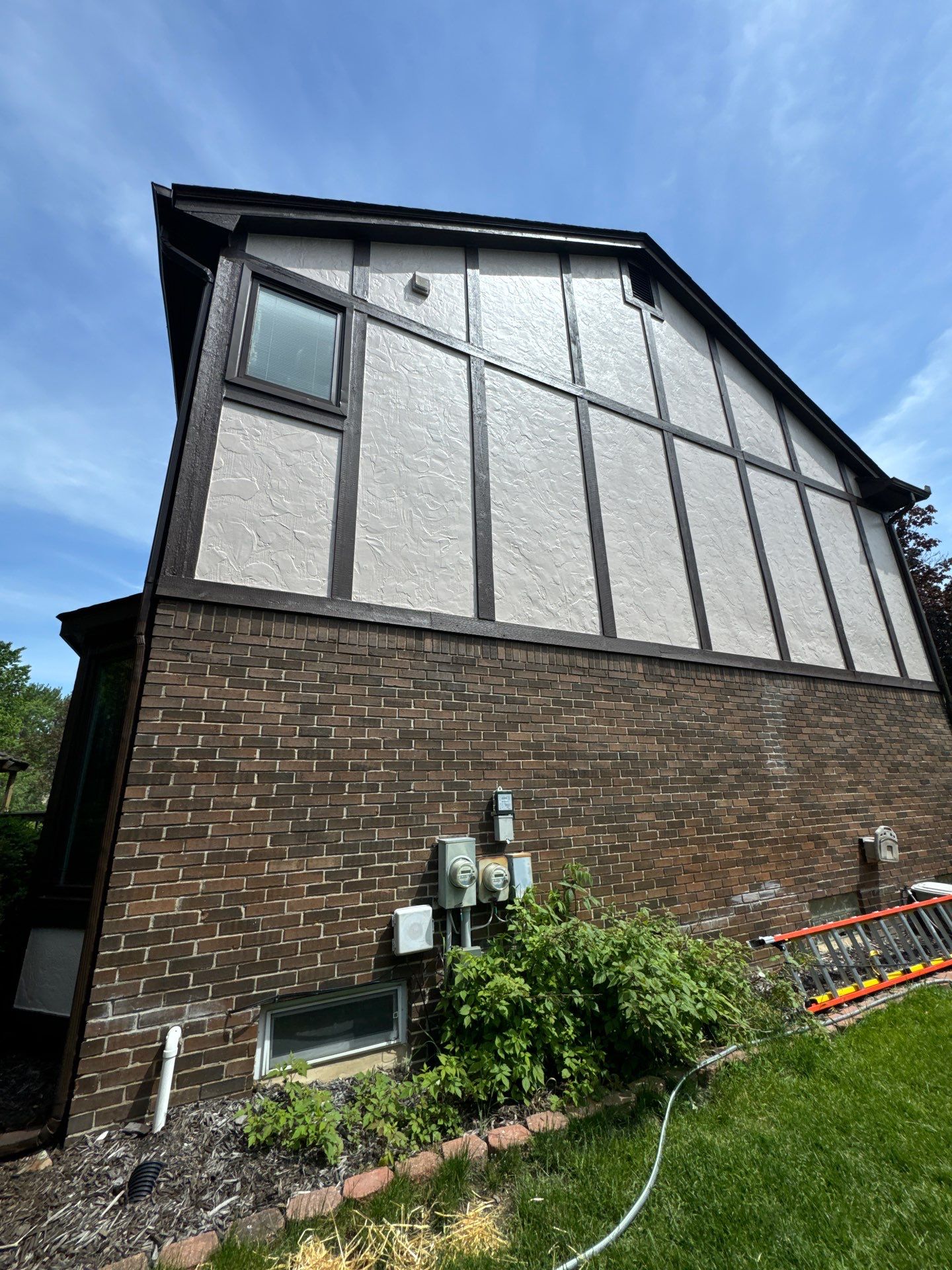 Completed Tudor House Exterior Painting Project Side view of a beautifully painted Tudor style house exterior with light stucco and dark timber framing.