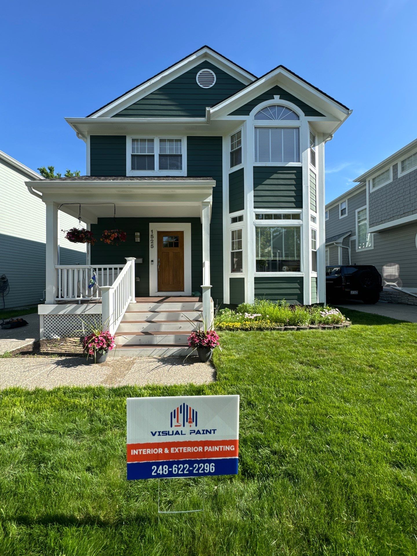Beautiful Green House Exterior Painting by Visual Paint Front view of a freshly painted green house with white trim, showcasing a painting company sign.