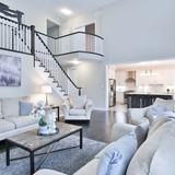Large living room painted white with stairway and view of kitchen